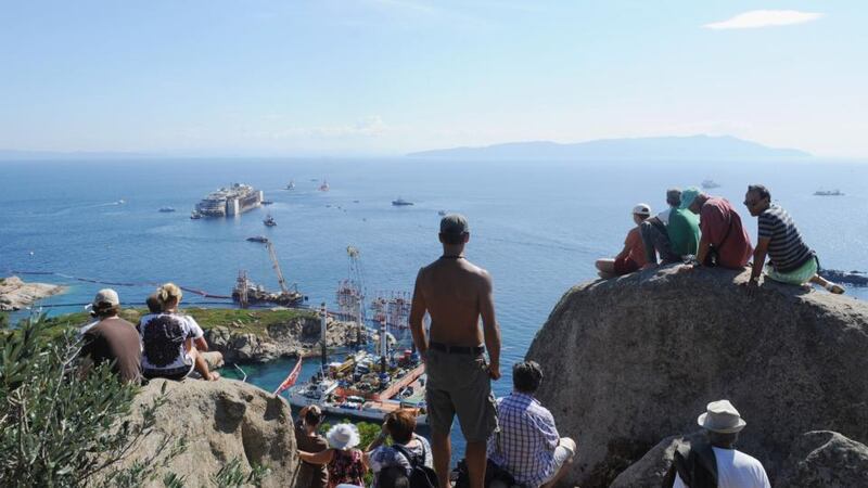People watch as the wrecked cruise ship Costa Concordia is towed by tugs from Giglio after being refloated today in Isola del Giglio, Italy. Photograph: Laura Lezza/Getty Images