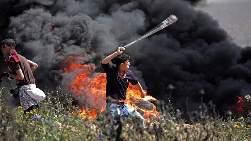 Palestinians protesters throw stones during clashes with Israeli troops, near the border with Israel in the east of Gaza City. Photograph: Mohammed Saber/EPA