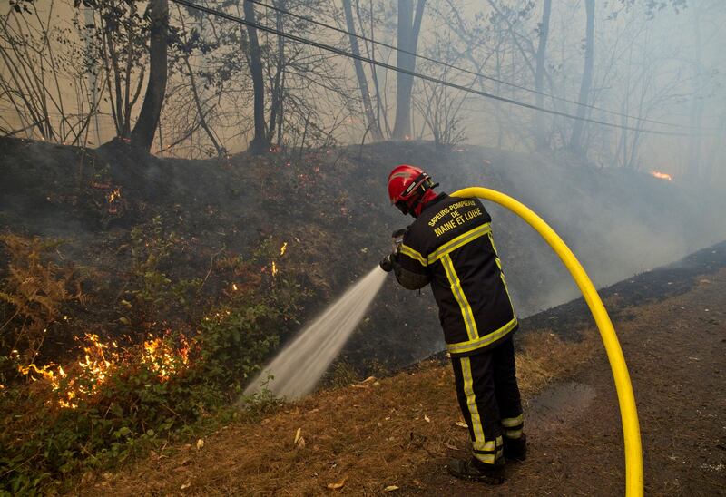 A firefighter uses a hose as a fire burns in a forest near homes in Clefs-Val-D'Anjou, near La Fleche, western France on August 9th. Photograph: Guillame Souvant/AFP via Getty Images