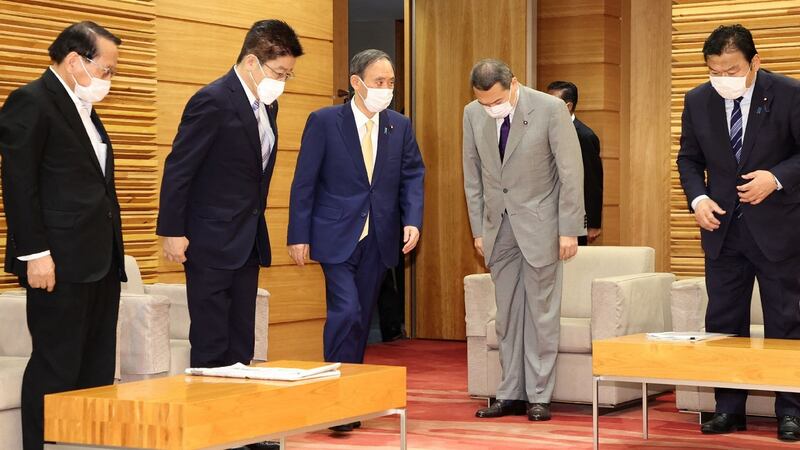 Japan’s prime minister Yoshihide Suga (centre, blue suit) arrives to attend a cabinet meeting at the prime minister’s office in Tokyo on Tuesday. Photograph: STR/Jiji Press/AFP via Getty Images