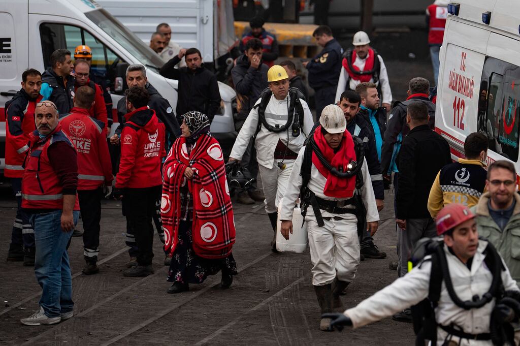 Rescuers walk past a woman waiting outside a coal mine after an explosion in Amasra, in Bartin Province, Turkey. Photograph: Yasin Akgul/ AFP/Getty