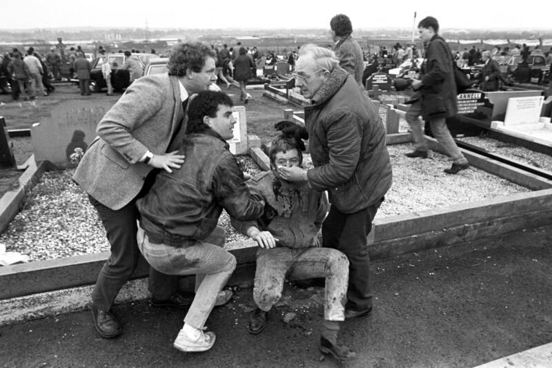 An injured man being aided by mourners, including Sinn Fein vice president Martin McGuinness (left), at Milltown Cemetery, Belfast, after a gun and bomb attack killed three and left four seriously injured, at the funerals in 1988 of three IRA members killed in Gibraltar. David Jones/PA Wire