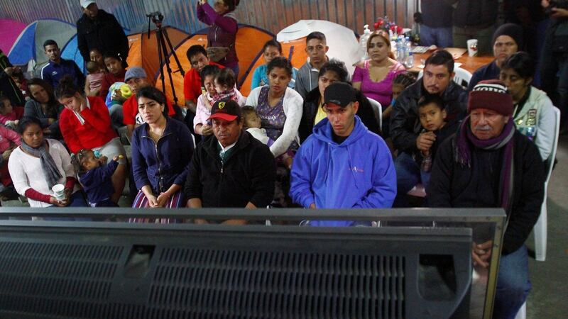 Migrants, part of a caravan of thousands from Central America trying to reach the United States, watch Donald Trump’s speech at a shelter in Tijuana. Photograph: Jorge Duenes/Reuters
