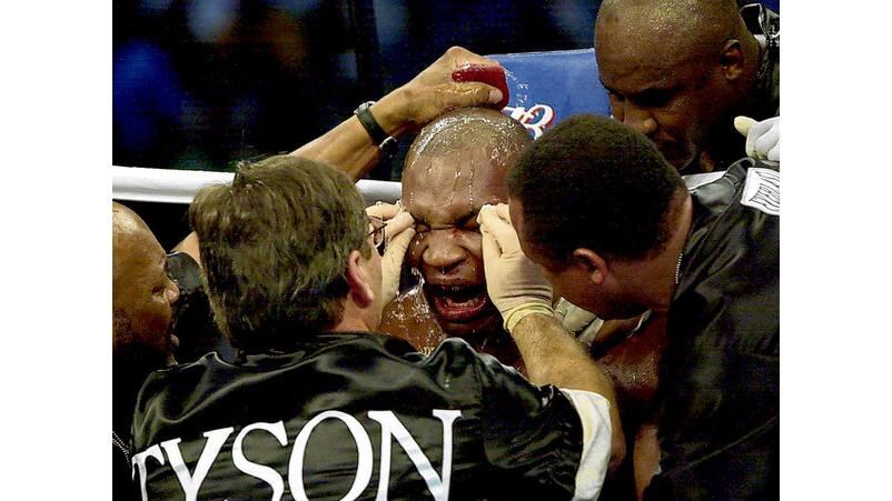 Tyson is clearly in some distress as his trainers attend to him in his corner midway through the fight. - (Photographs: Getty Images and AP).