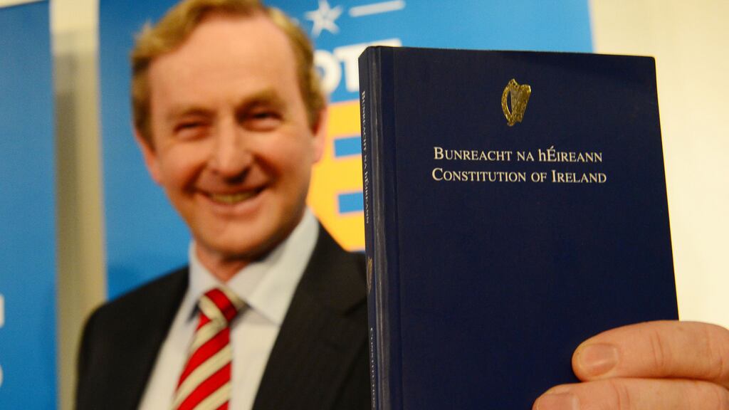 Taoiseach Enda Kenny holding a copy of Bunreacht na hÉireann, which will now contain gender-neutral language in relation to the institution of marriage. Photograph: Bryan O’Brien