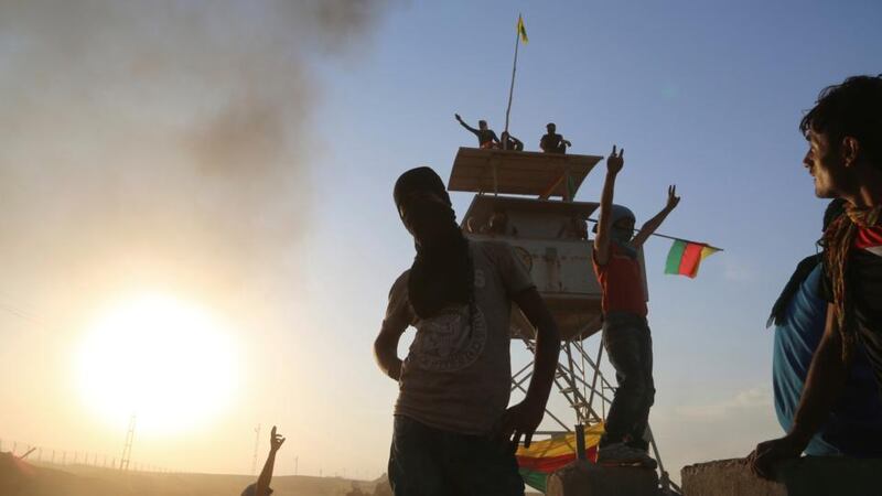 Kurdish protesters gesture as they occupy a post for Turkish border guards yesterday during a protest demanding that the Turkish government do more to help Kobani, in the northeast Syrian Kurdish city of Qamishli bordering the Turkish town of Nusaybin. Photograph: Dyar Hasso/Reuters