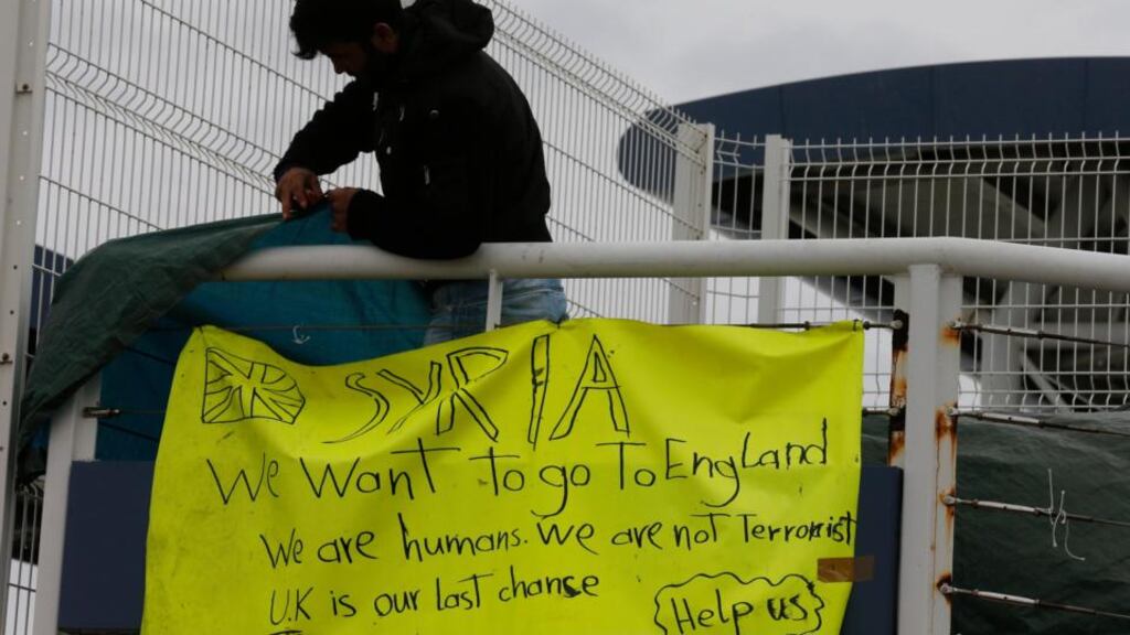 Kamal, a 25-year-old Syrian asylum seeker who fled Aleppo two months ago, removes a banner on a footbridge after ending a demonstration at the ferry terminal in Calais, northern France, last week. Photograph: Pascal Rossignol/Reuters.