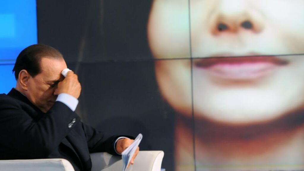 Italian Prime Minister Silvio Berlusconi is seen while a portrait of his wife Veronica Lario is projected in the background. Photograph: Tiziana Fabi/AFP/Getty Images