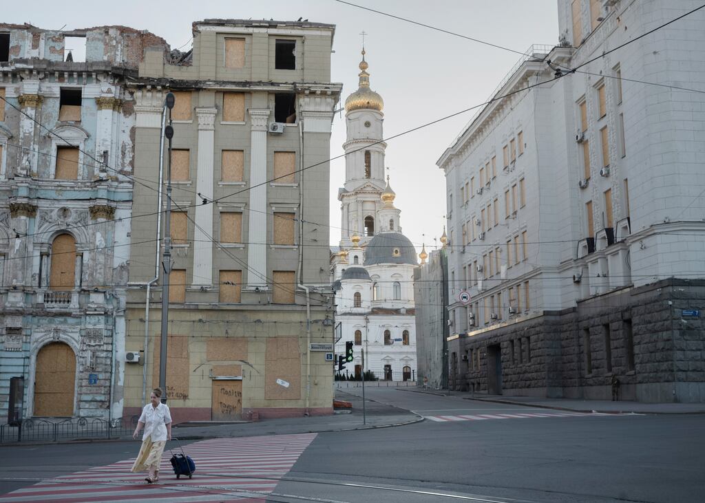 A woman walks past buildings damaged by Russian strikes in Kharkiv, Ukraine. Kharkiv officials said on Thursday that Russia had bombed the municipal council building in Kupiansk overnight, injuring two people. Photograph: Emile Ducke/New York Times