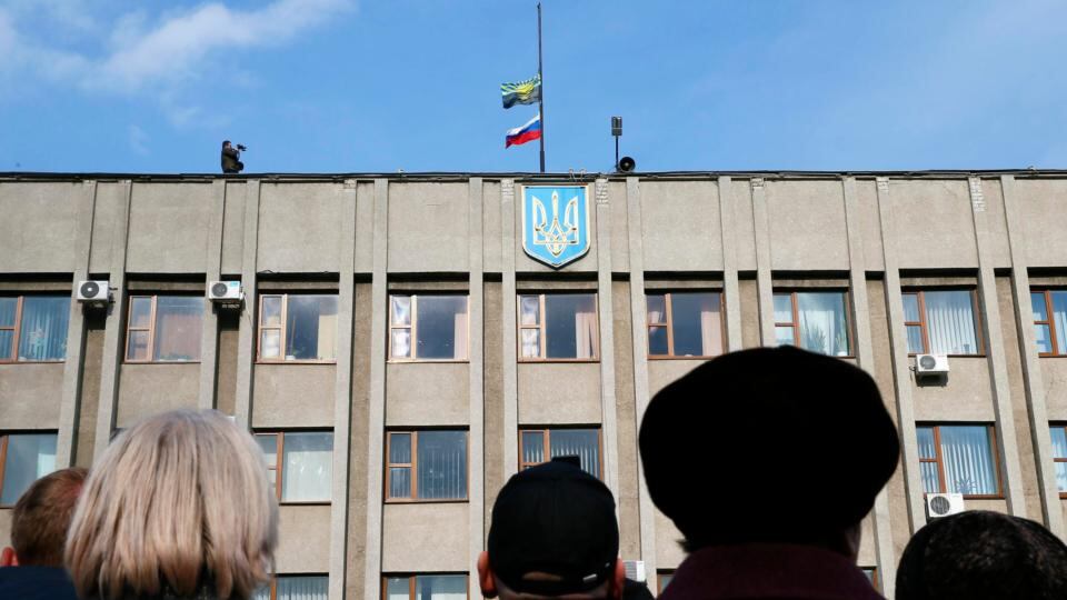 Pro-Russian supporters gather in front of the mayor’s office, as the flags of Russia (bottom) and Donetsk region are seen on the rooftop, in Slaviansk  today. Photograph:  Gleb Garanich/Reuters.
