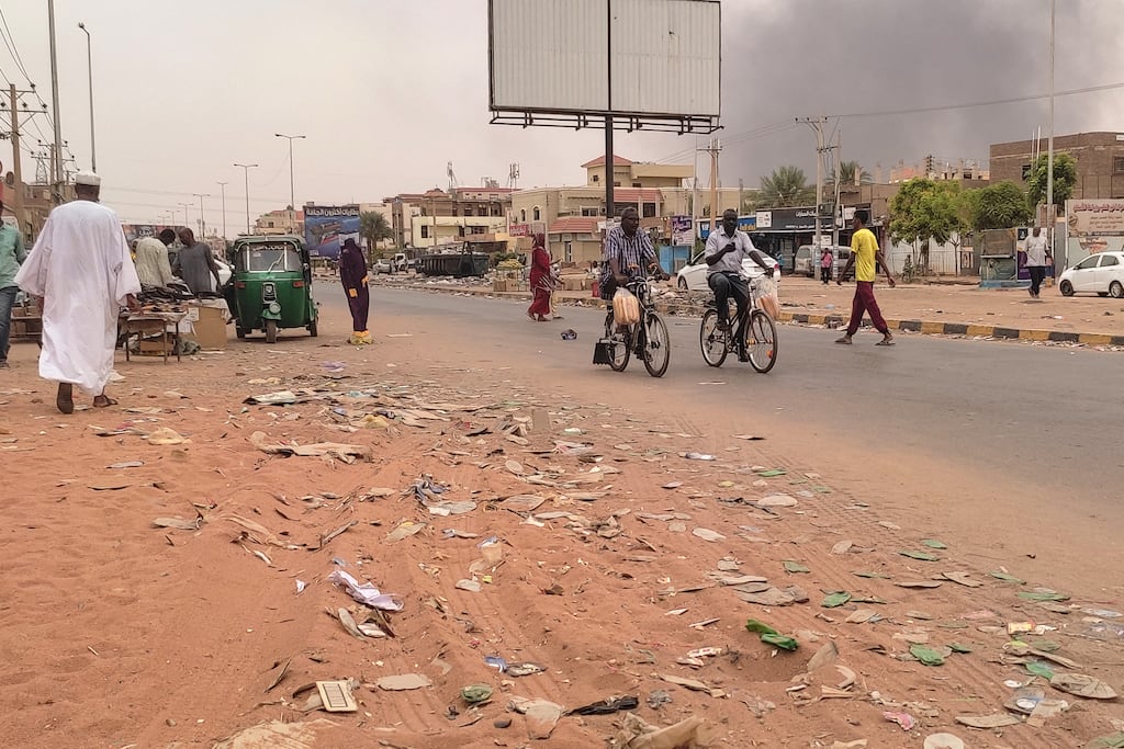 Smoke rises above buildings as people walk along a street in Omdurman on July 15th, 2023. Photograph: AFP via Getty Images