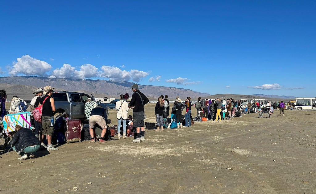 People waiting for a bus to leave the Burning Man festival in Black Rock City, Nevada. Heavy rains stranded as many as 70,00 people and forced organisers to shut down the road leading into and out of the festival. Photograph: EPA