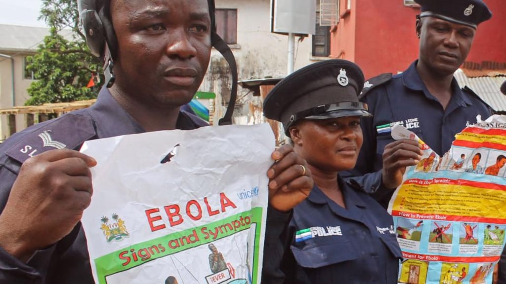 Police officers hold up posters about Ebola in Freetown, Sierra Leone. Photograph: Youssouf Bah/AP