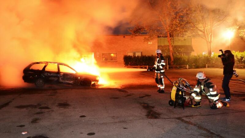 Firefighters extinguish a burning car, following riots in the Stockholm suburb of Kista last night. Photograph: Fredrik Sandberg/Scanpix/Reuters