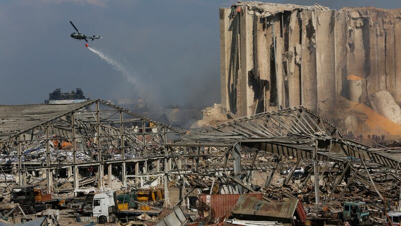 A helicopter drops water on smoldering buildings in Beirut, destroyed by an explosion a day earlier. Photo: Marwan Tahtah/Getty Images