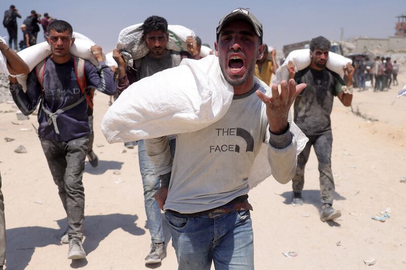 A man reacts as he walks with others carrying sacks of flour delivered after trucks carrying humanitarian aid entered northern Gaza on July 27th Photograph: AFP via Getty Images