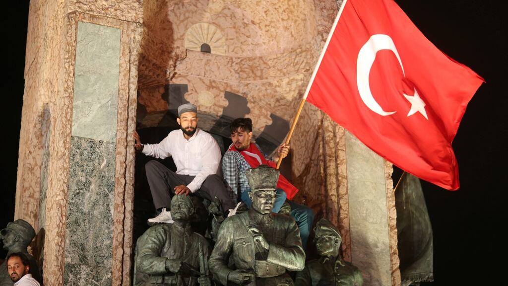 Supporters of Turkish president Recep Tayyip Erdogan sit on a statue of Ataturk, the founder of modern Turkey, as they shout slogans and hold flags during a demonstration against the failed coup attempt, at Taksim Square, in Istanbul on Wednesday. Photograph: Tolga Bozoglu/EPA