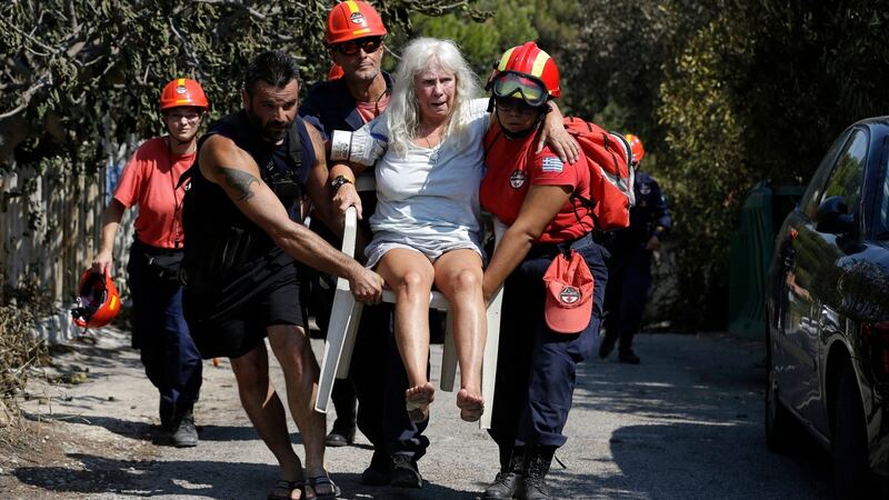 Members of a rescue team carry an injured woman in Mati, Greece on Wednesday. Photograph: Thanassis Stavrakis/AP