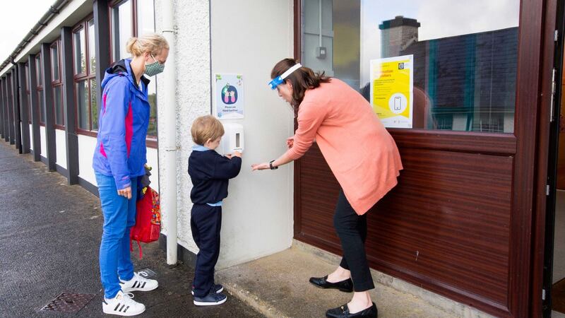 Ryan Gilrane sanitises his hands before entering school on his first day under the watchful eye of his mother, Christine, and teacher, Jacinta Greene. Photograph: Brian Farrell/The Irish Times