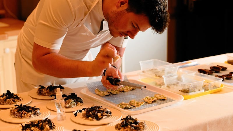 Crisp cod skin with smoked cod roe, burnt chive emulsion and summer preserves being finished off.