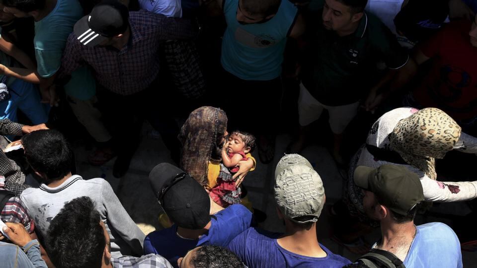 Syrian men form a safety passage for women following clashes during a registration procedure in the national stadium of the Greek island. Photograph: Yannis Behrakis/Reuters
