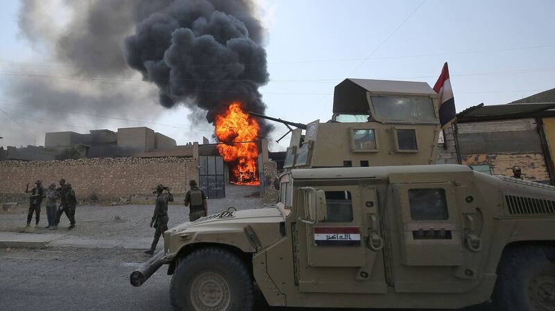Smoke billows from a burning building as an Iraqi forces Humvee advances along  a street in  Tal Afar, west of Mosul. Photograph: Ahmad Al-Rubaye/AFP/Getty Images