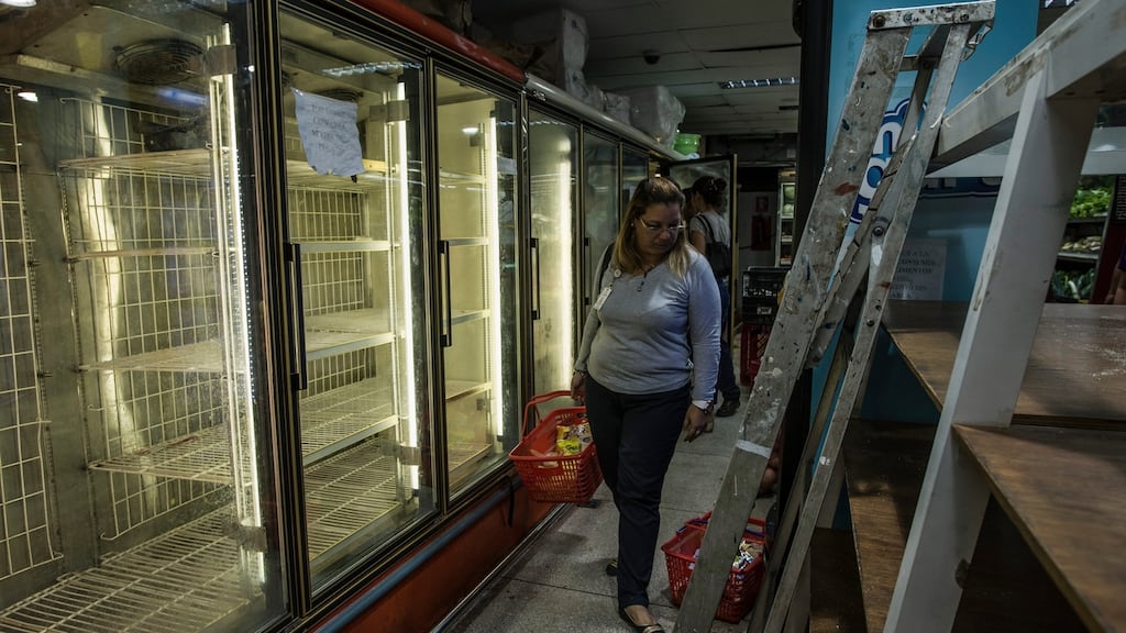 A shopper passes an empty fridge in a supermarket in Cumana, Venezuela. A recent survey  showed 87 per cent of Venezuelans said they did not have enough money to buy food. Photograph: Meridith Kohut/New York Times