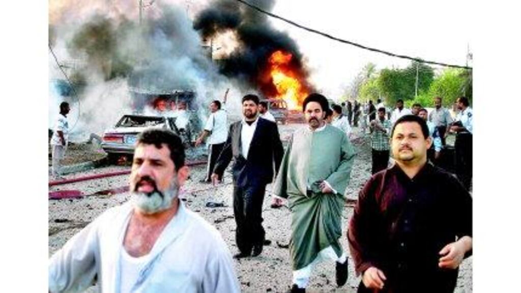 Iraqis at the scene of one of three explosions that hit the city of Basra early yesterday. The almost simultaneous blasts hit three police stations, killing at least 68 and injuring over 200, a hospital source said. Some of the victims were children on their way to kindergarten