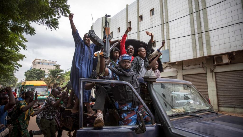 Malians climb onto a police vehicle and cheer as it drives through the streets of Bamako on Wednesday. Photograph: H Diakite/EPA