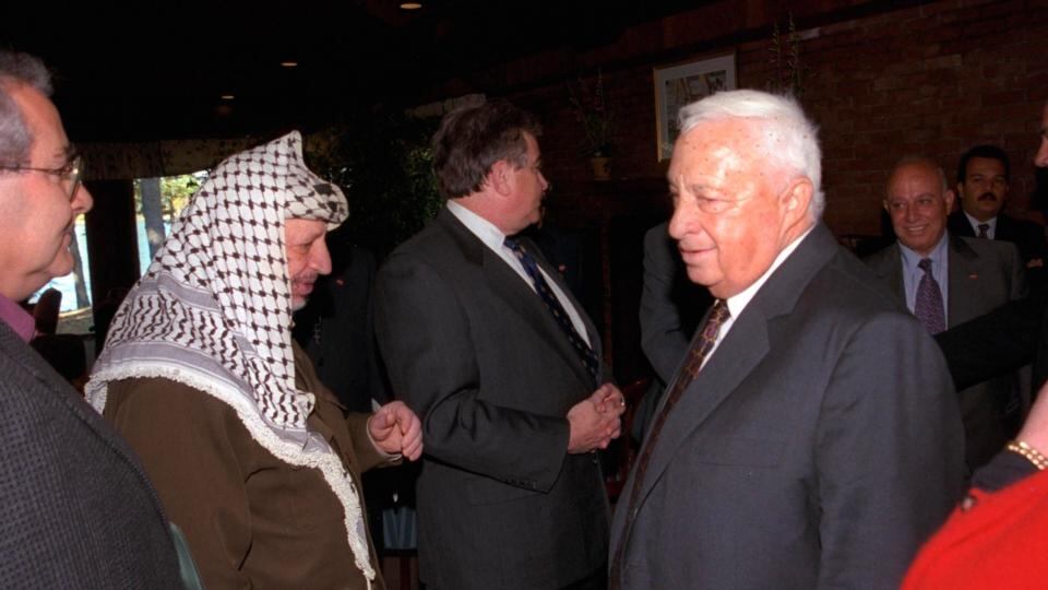 Israel’s foreign minister Ariel Sharon walks past Palestinian Leader Yasser Arafat during the Middle East peace summit at the Wye River Conference centre in  1998. File Photograph: Israeli Government Press Office/Reuters