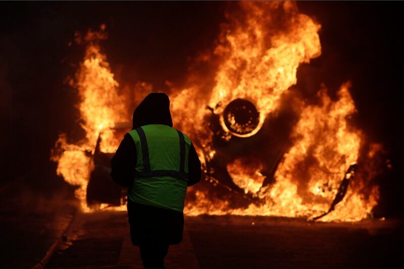 A demonstrator watches a burning car near the Champs-Elysees avenue in Paris during a Yellow Vests demonstration on Saturday, December 1st Photograph: Kamil Zihnioglu/AP
