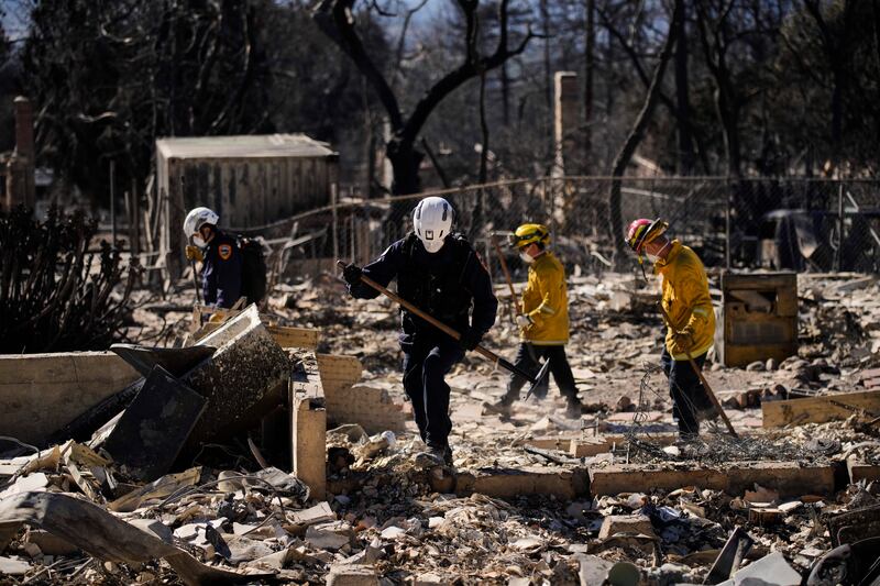 A search-and-rescue crew sifts through the wreckage of a home destroyed by the Eaton fire in Altadena, California. Photograph: John Locher/AP