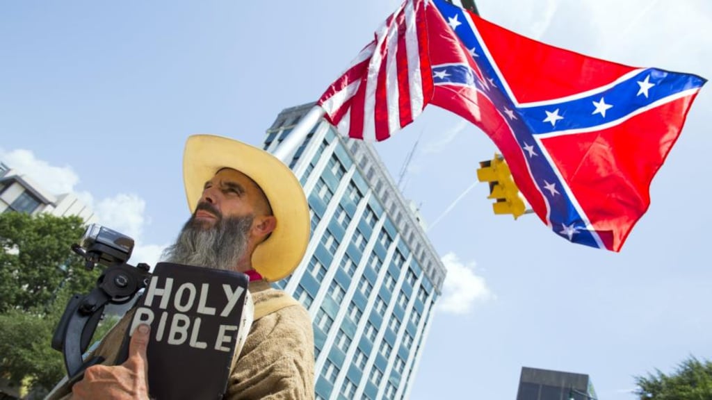 Man holds a confederate battle flag and Bible outside the statehouse in Columbia, South Carolina, on Thursday, just hours before Gov Nikki Haley signed a Bill to remove the flag from statehouse grounds. Photograph: Jason Miczek/Reuters