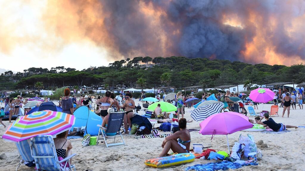 People sunbathing on  a beach watch smoke from a forest fire billowing into the sky in Bormes-les-Mimosas, southeastern France, on July 26th, 2017.Photograph: Anne-Christine Poujoulat/AFP/Getty Images