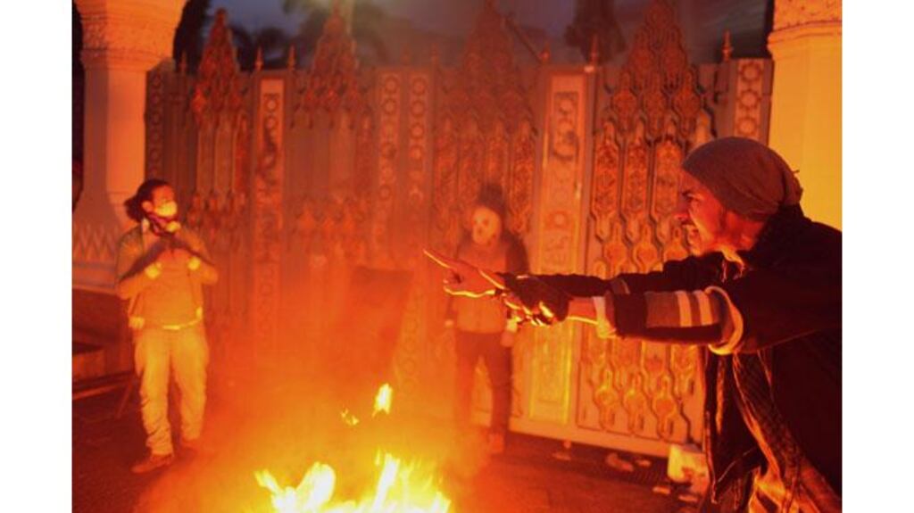 Protesters stand in front of one of the gates of the presidential palace, as they threw a molotov cocktail in front of the gate and tried to break through the gate, in Cairo today. Photograph: Asmaa Waguih/Reuters