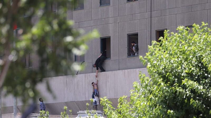 Iranian policemen try to help some civilians fleeing from the parliament building during an attack in Tehran. Photograph:  EPA