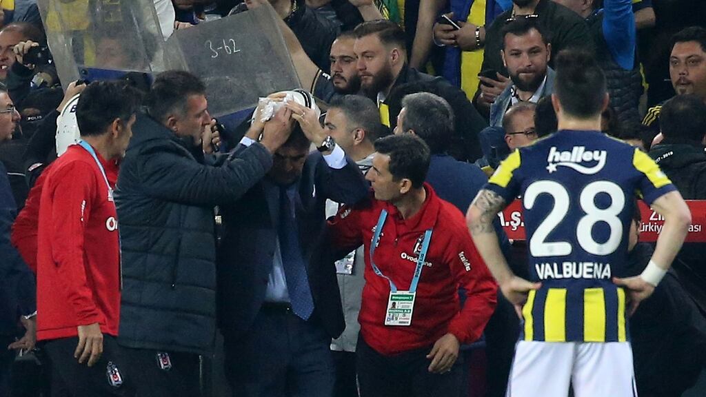 Besiktas manager Senol Gunes holds his head after being hit by a missile during a Turkish Cup semi-final against Fenerbahçe. Photograph: Stringer/AFP