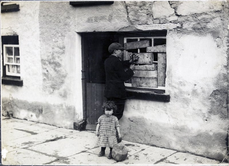 A boy boards up a window in Templemore, Co Tipperary, in 1920 after a British military reprisal. Photograph: Courtesy of National Library of Ireland