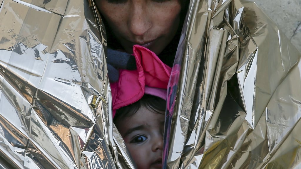 A migrant, wrapped with her child in a thermal blanket, waits for a train to Croatia, at a train station in Presevo, Serbia. Photograph: Marko Djurica/Reuters