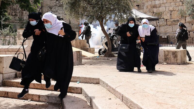 Palestinians run for cover from tear gas fired by Israeli security forces in Jerusalem’s Old City on Monday. Photograph: Emmanuel Dunand/AFP via Getty Images