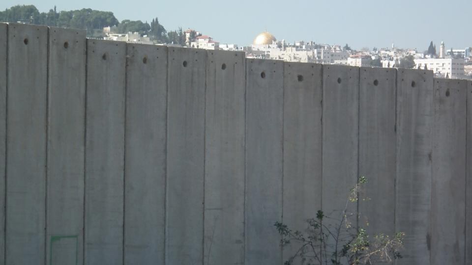 In 2013, I spent a semester teaching literature at Al-Quds University in the West Bank. From the main gate of the university’s campus in Abu Dis, the first thing you see is the Wall. It was built in 2002 and it was originally set to cut the campus in half. If you stand on the road outside campus, Jerusalem appears as a thin line, with the golden Dome of the Rock at its centre, caught between the horizon above and the Wall below