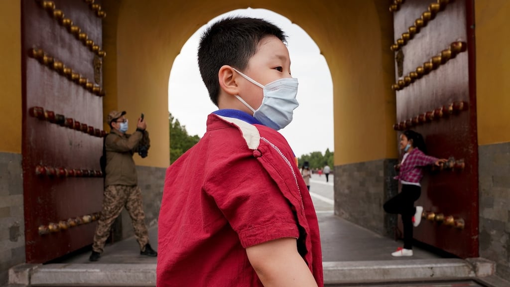 Two Chinese kids wear protective masks as they visit the Temple of Heaven in Beijing, China. Photograph: Lintao Zhang/Getty