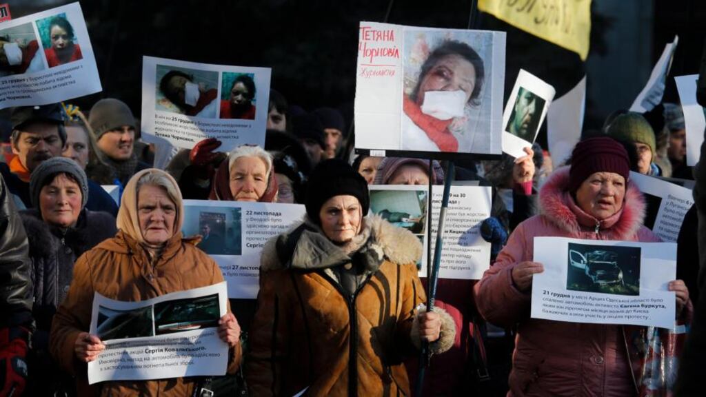 Protesters hold images depicting the badly beaten face of Ukrainian journalist Tetyana Chornovil during a protest in front of the interior ministry building in Kiev yesterday. Photograph: Sergey Dolzhenko/EPA