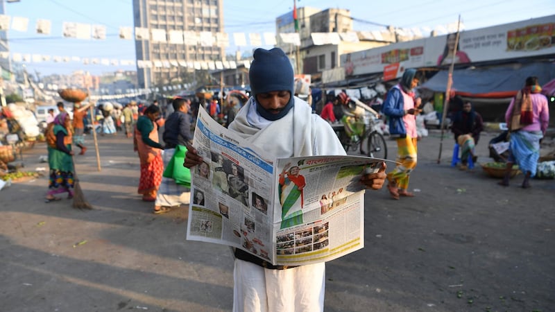 A man reads a newspaper carrying headlines of the general election results in Dhaka on New Year’s Eve. Photograph: Indranil Mukerjee/ AFP/Getty Images