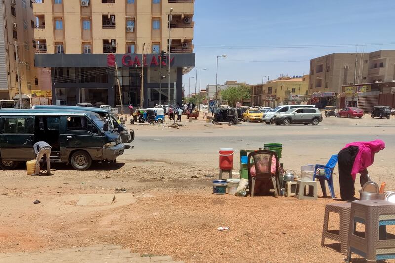 A man sells fuel in containers (L) and a woman sells drinks in a street in southern Khartoum, on May 4, 2023. - Gunfire and explosions gripped Khartoum for a 20th straight day leaving the latest ceasefire effort in tatters, a day after UN chief Antonio Guterres acknowledged the international community had "failed" Sudan. (Photo by AFP) (Photo by -/AFP via Getty Images)
