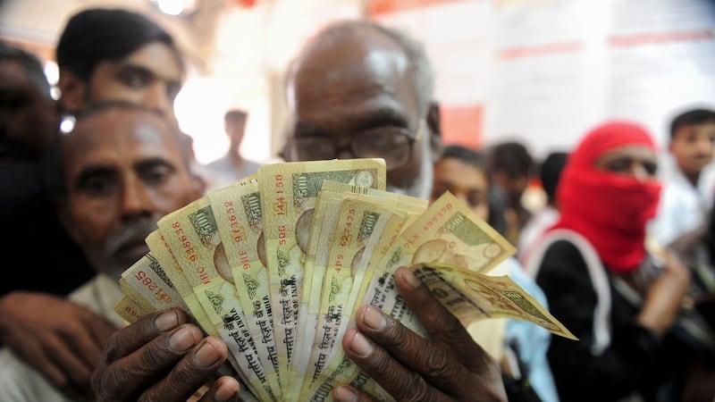 A man holds up old newly-demonetised 500 rupee notes as people queue inside a bank in Rahimapur village, on the outskirts of Allahabad, India, to deposit high denominational notes on Thursday. Photograph: Jay Kanojia/AFP/Getty Images