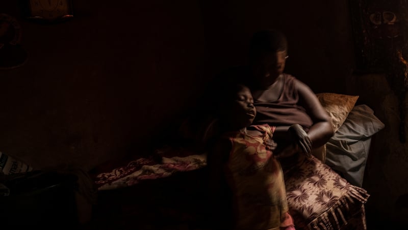 Nono Zubeda picks up her nine-year old daughter Salma Kobusinge after she falls over in their two-bedroom home. Photograph: Christopher Hopkins