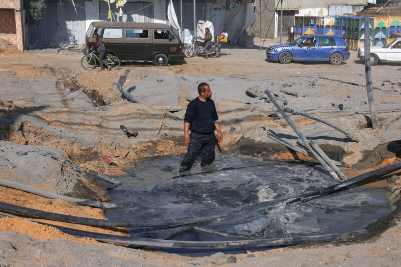 A Palestinian man stands in a crater filled with water following an Israeli airstrike on the main road between Rafah and Khan Younis on Saturday. Photograph: Ssaid Khatib/AFP via Getty Images