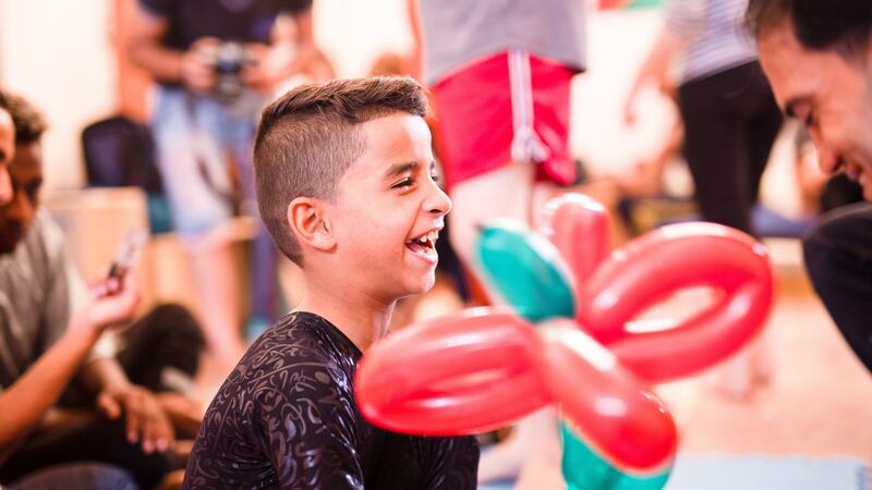 Muneer Salah giggles as Alaa Meqdad entertains him with balloon animals