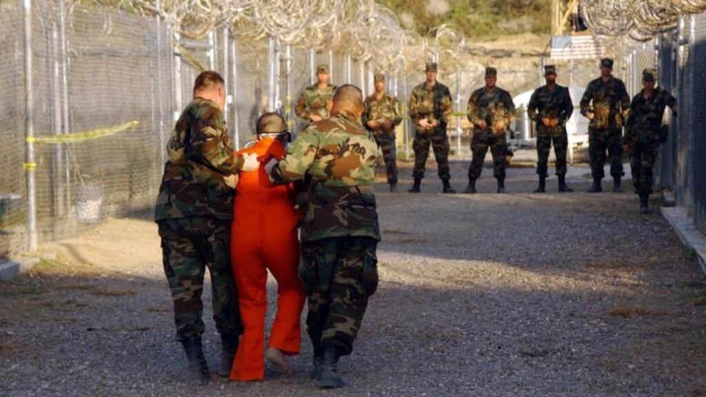 A US department of defence handout photograph of US army military police escorting a detainee to his cell in Camp X-Ray at Naval Base Guantánamo Bay, Cuba, on January 11th, 2002.